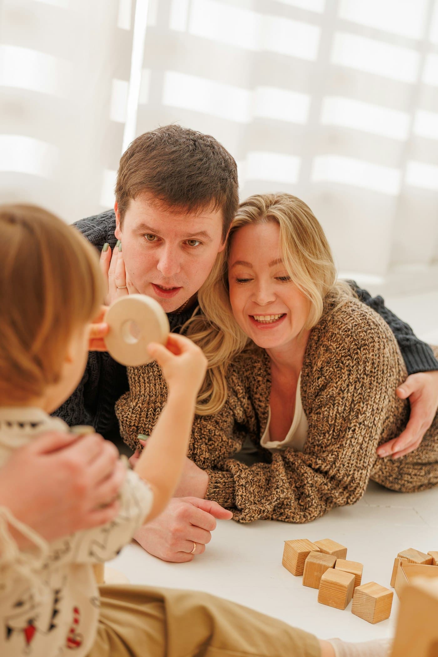 Parents playing with their toddler and wooden blocks at home